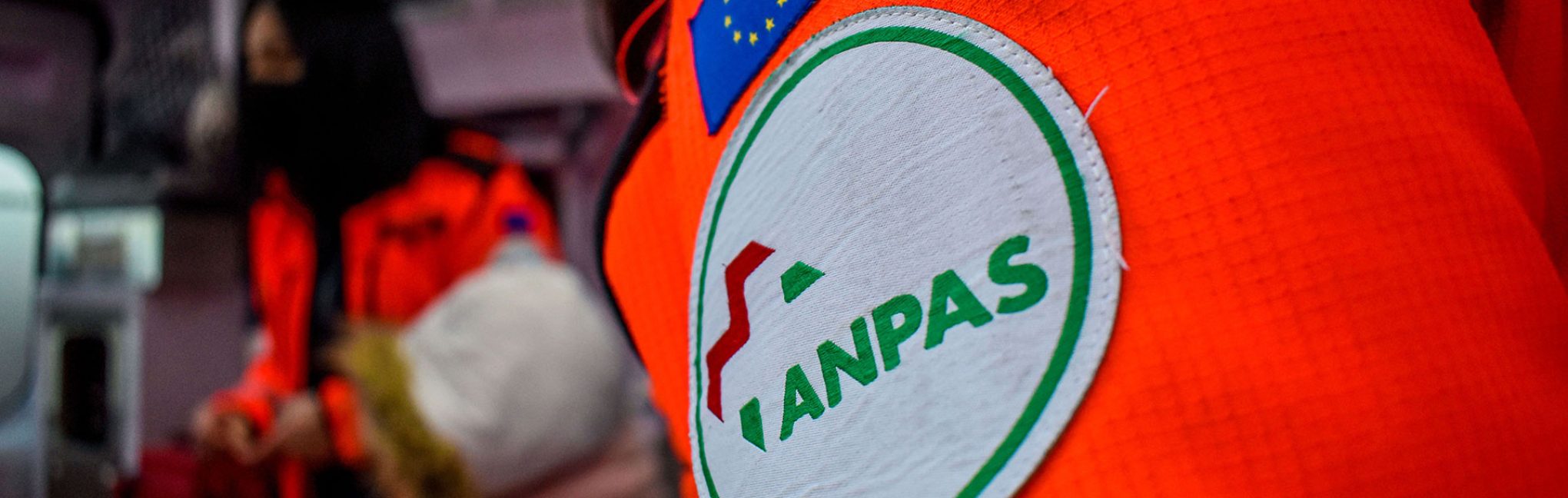 Dettaglio della divisa di un volontario con logo ANPAS all’interno di un’ambulanza